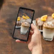 man taking vertical video of coffee and cake