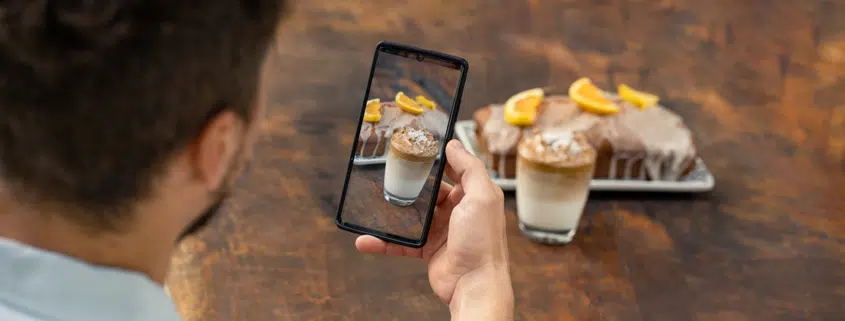 man taking vertical video of coffee and cake