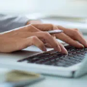 hands typing on a computer while reviewing owned media