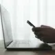 hands-holding-phone-over-computer